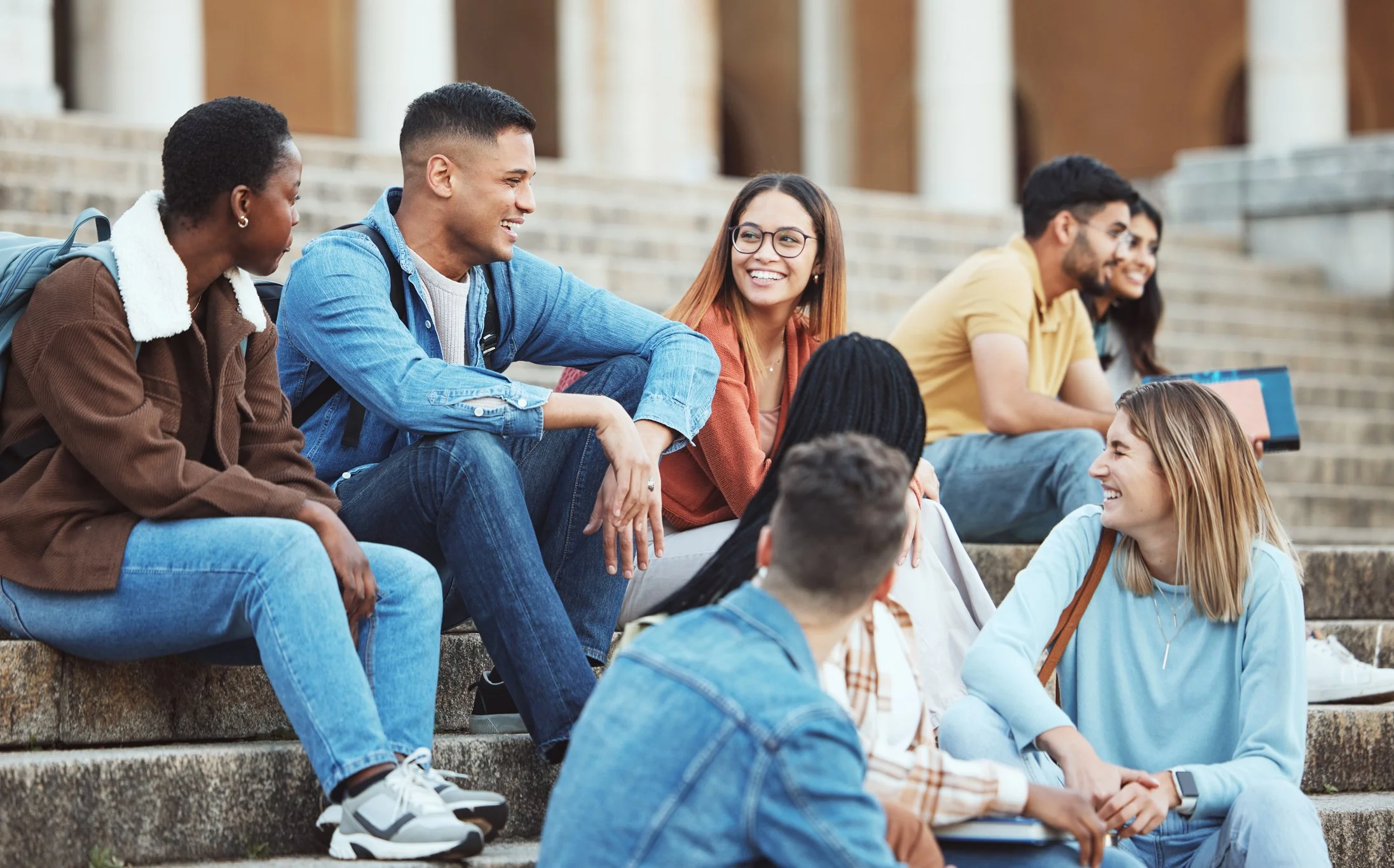 Young adults talking together on outdoor steps.