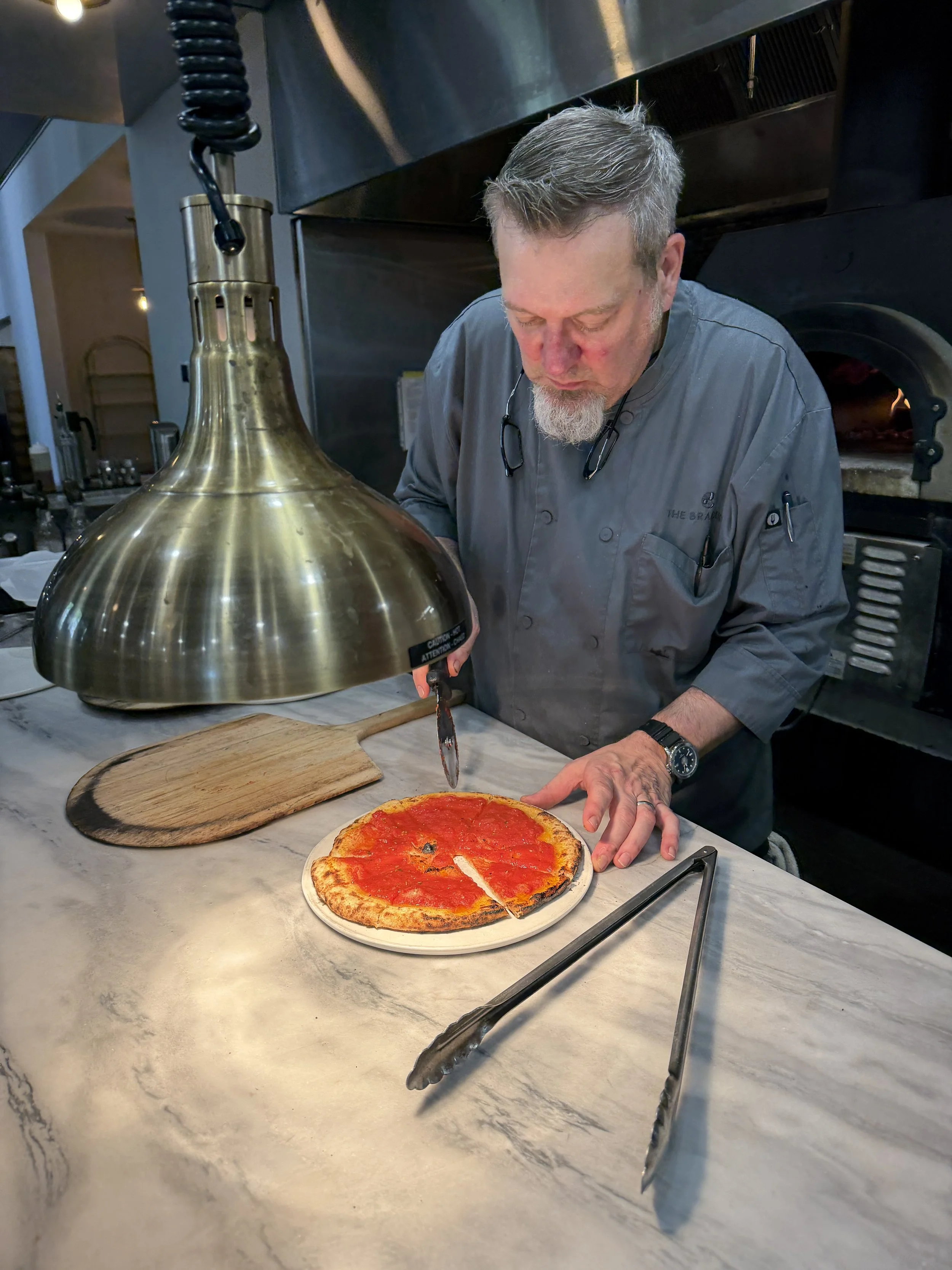 A chef slicing pizza on a countertop.