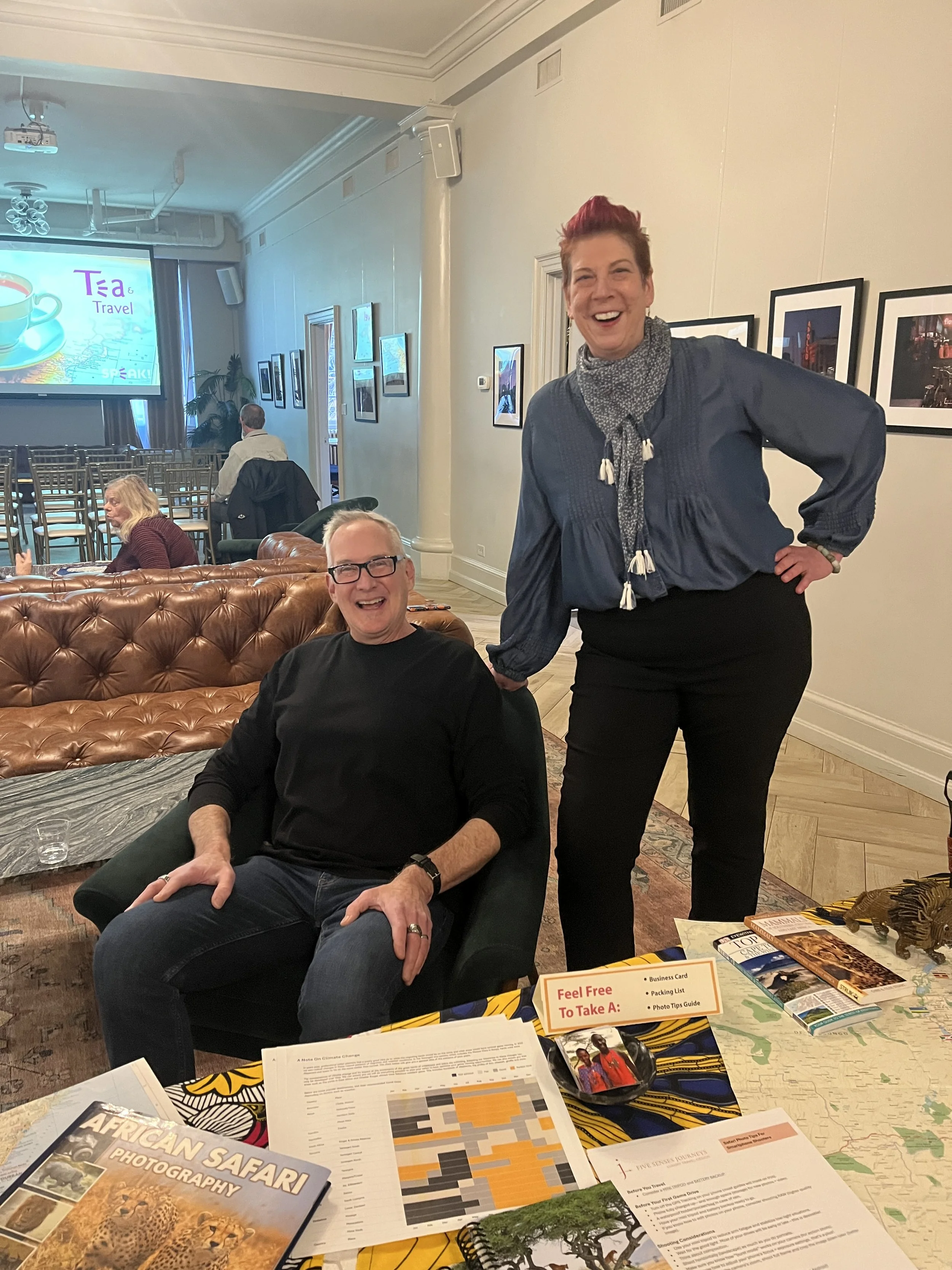 Two people at a table with travel brochures and photography information.
