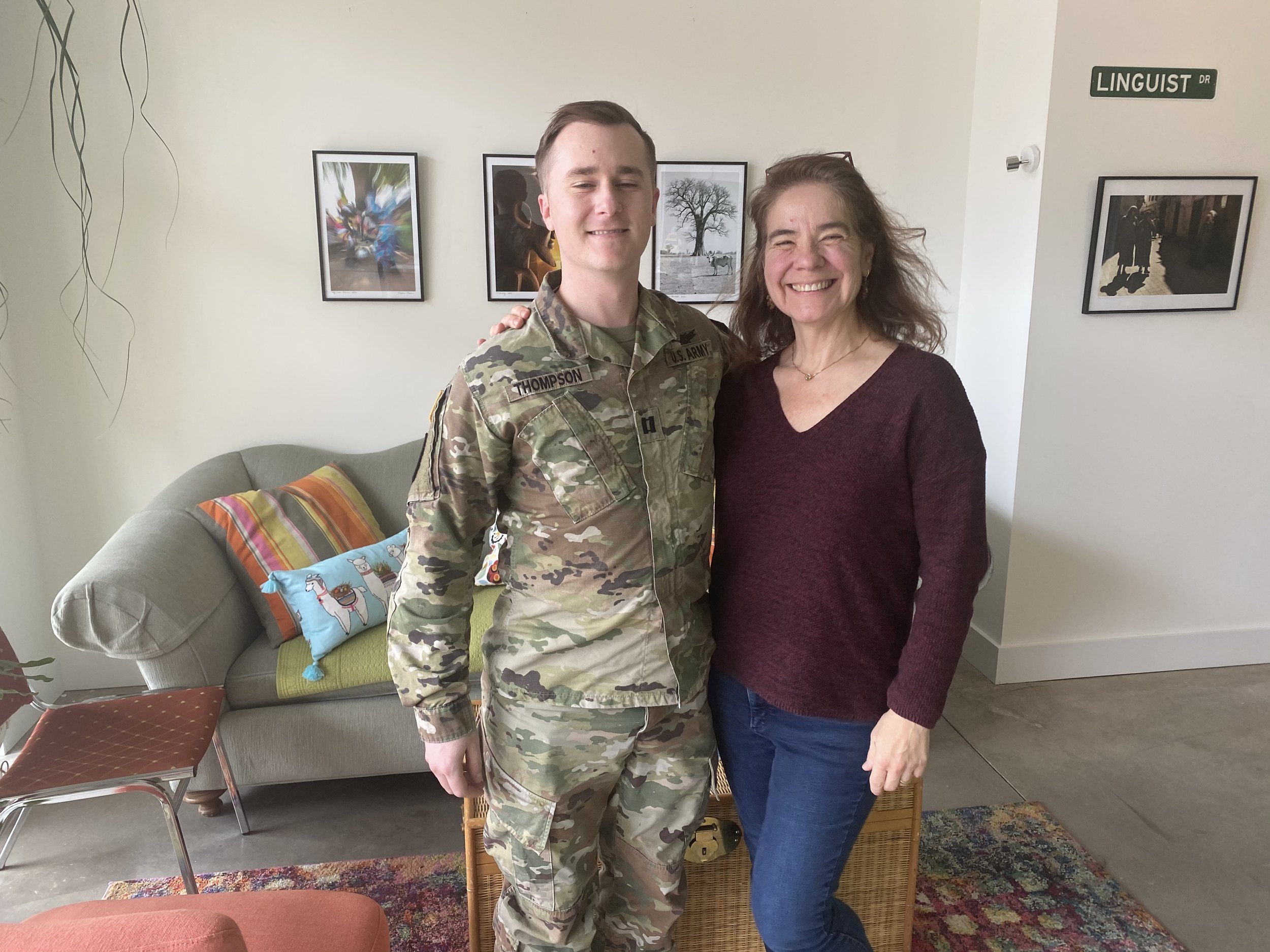 A man in camouflage uniform and a woman smiling together indoors.