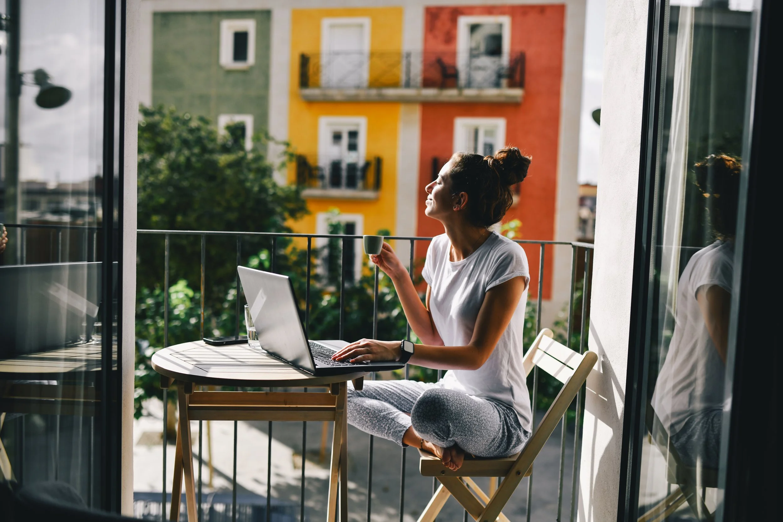 A woman using a laptop at a balcony table.