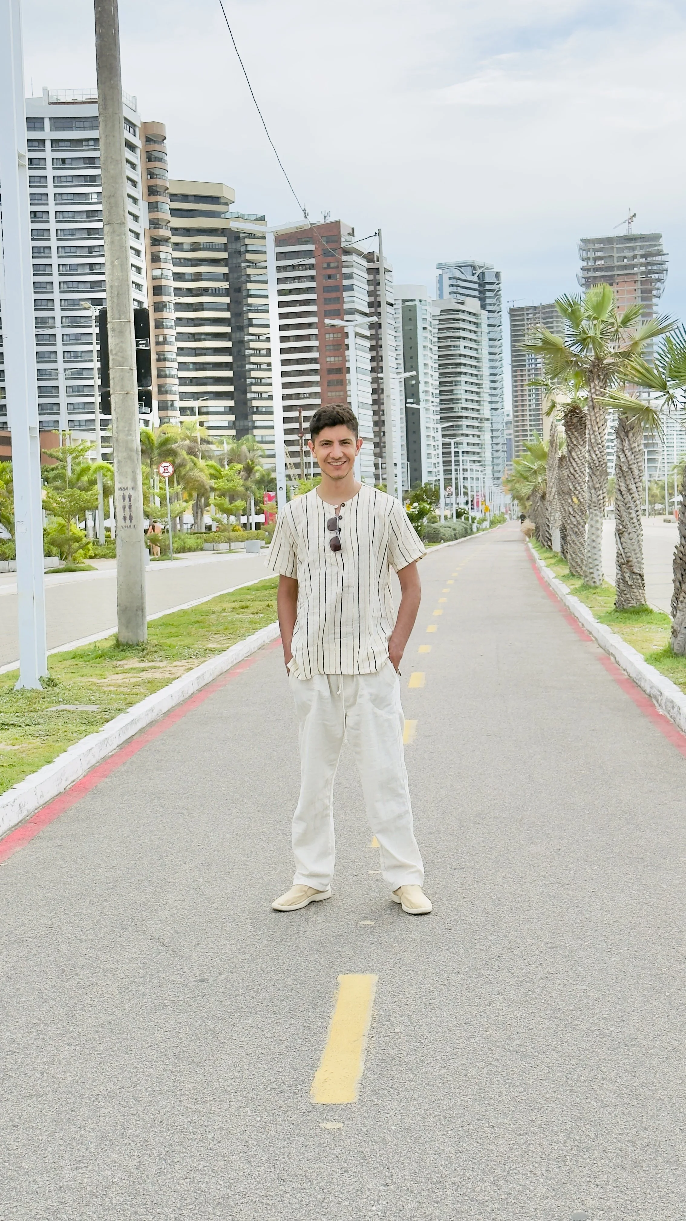 A man standing on a path lined with palm trees.