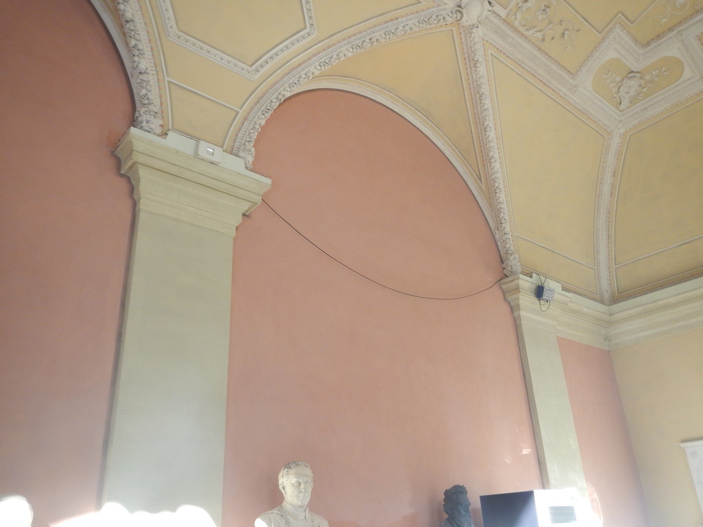 Innenraum mit kunstvoll gestalteter Decke, alten Büsten und Wanddekorationen in einem historischen Gebäude. Fassaden arbeiten von bmk-projekt umgesetzt in Wien.