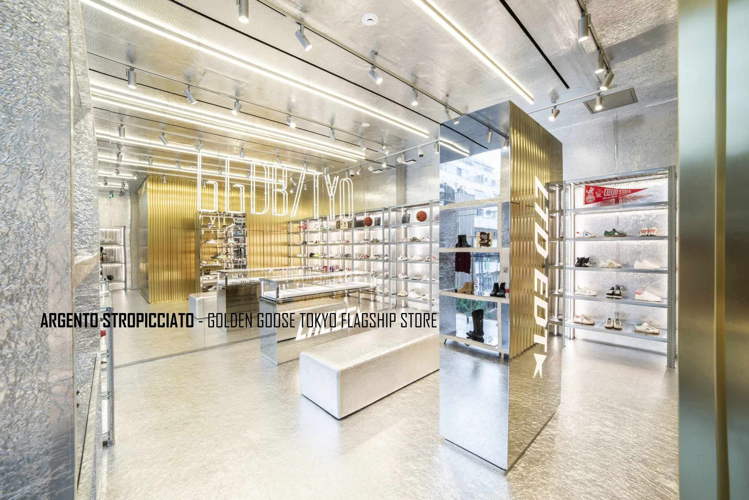 Interno di un negozio di scarpe con scaffali di scarpe e attrezzature metallici, decorazioni dorate e neon