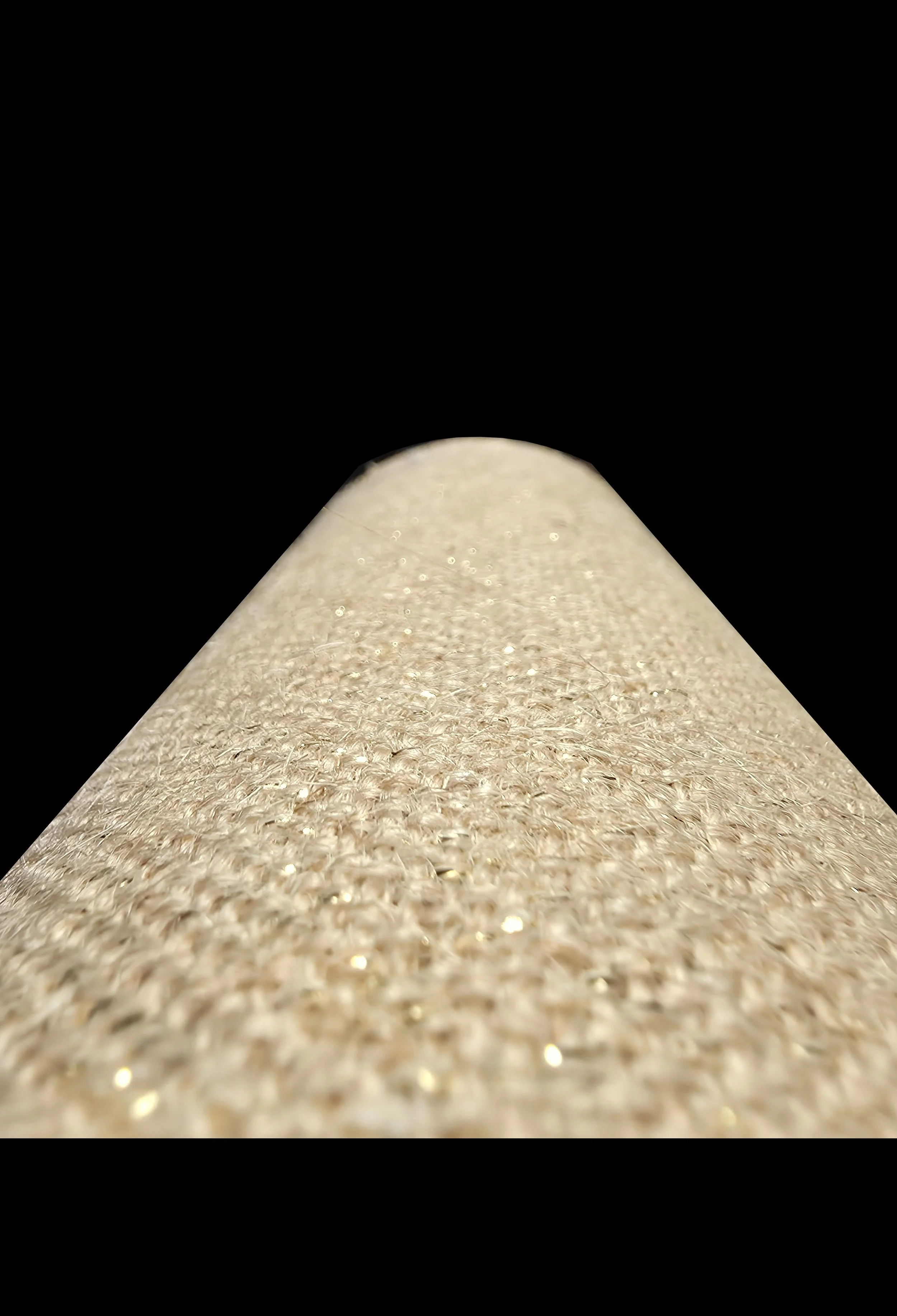 Close-up di una superficie luminosa con dettagli brillanti, sfocata verso l'esterno, su uno sfondo nero.