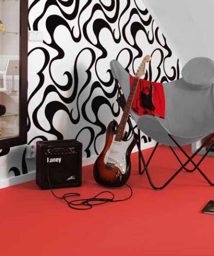 Entra in una stanza con pareti decorate con un motivo astratto nero e bianco, uno stereo Laney, una chitarra elettrica e una sedia moderna grigia.