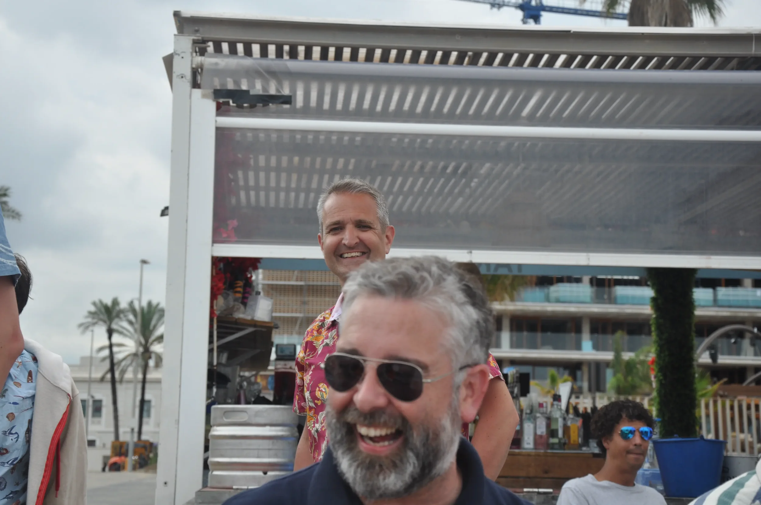 Group of people enjoying a day outdoors with palm trees in the background, smiling and having a good time near a food cart.