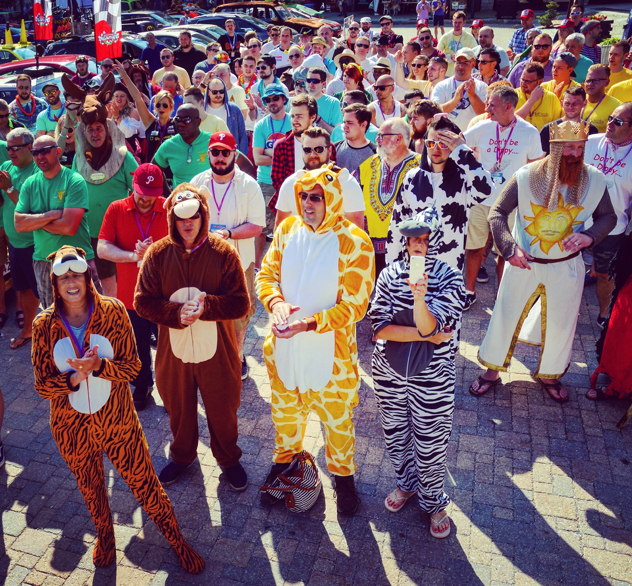 Group of people wearing animal onesies and costumes at outdoor event.