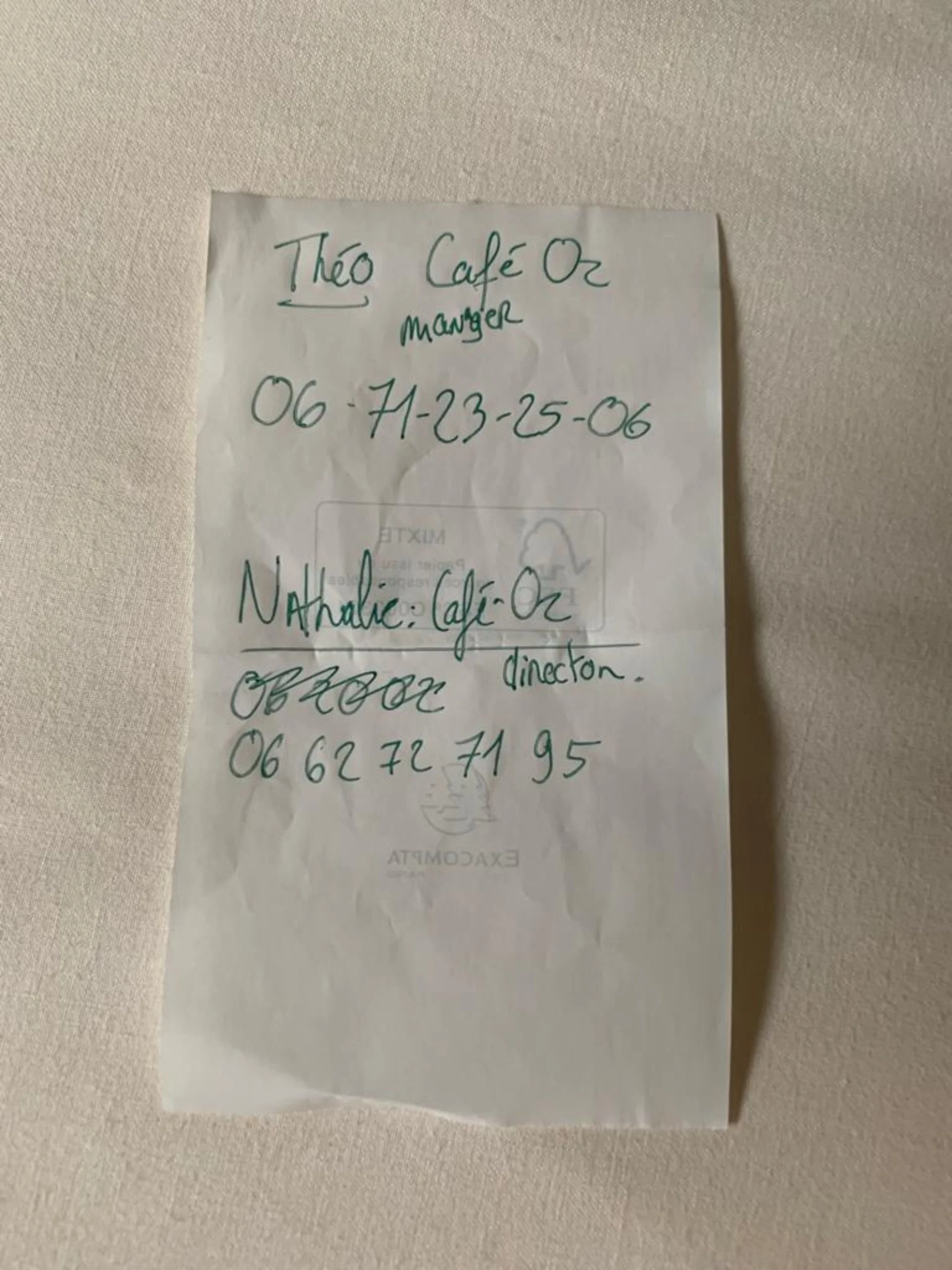 A handwritten note on a piece of paper with contact information, including a name, phone number, and directions, taped to a textured wall.