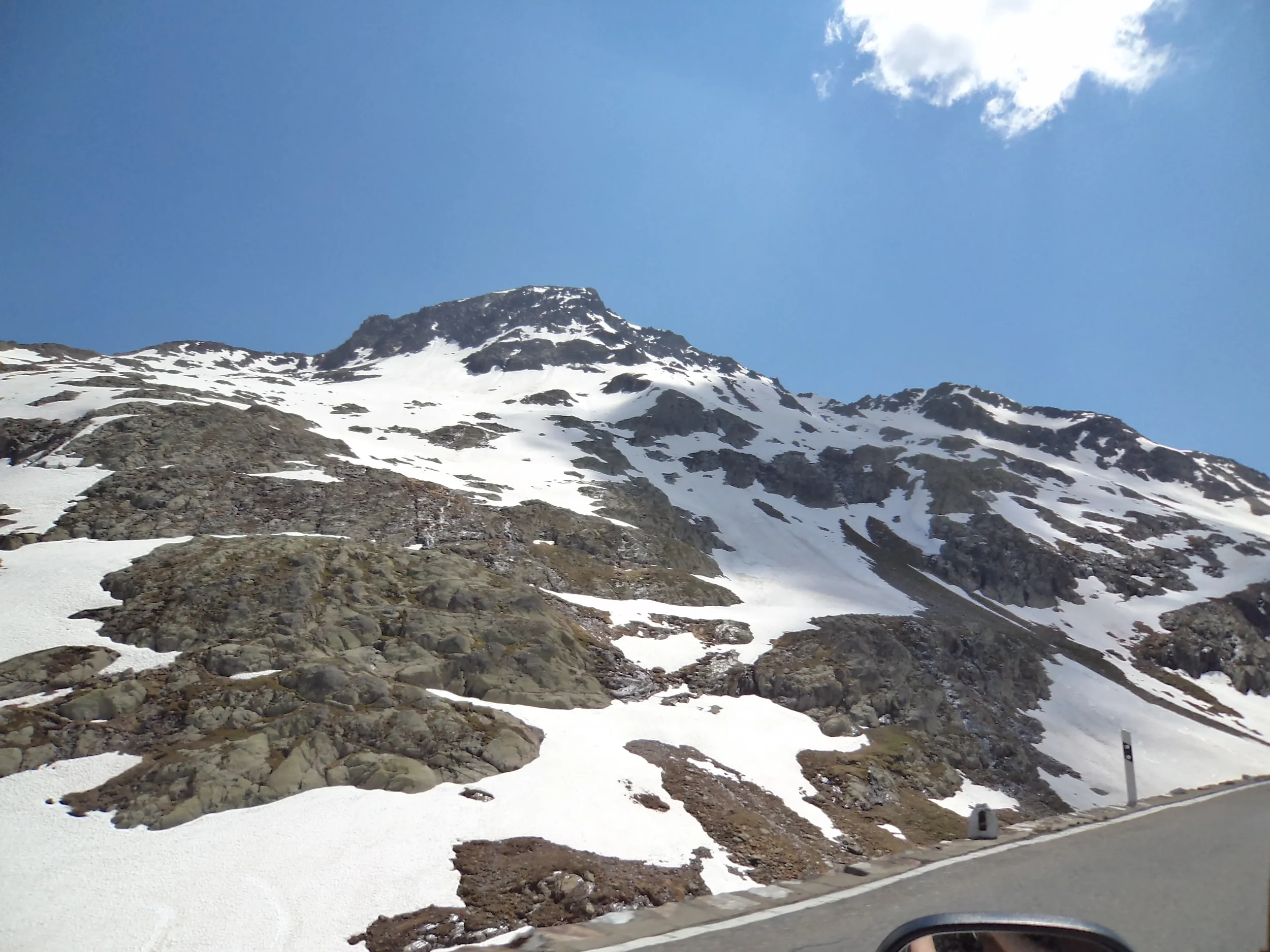 Snow-covered mountain slope with rocks and a clear blue sky.