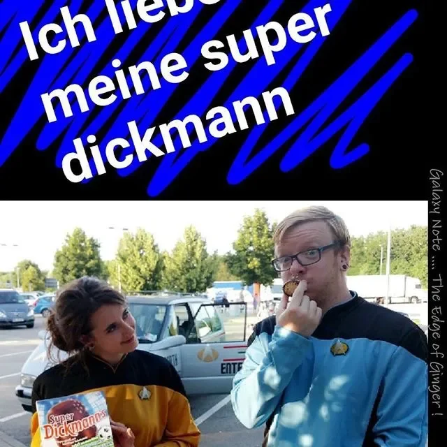 A young woman dressed as a Star Trek crew member stands next to a young man dressed as a Star Trek crew member in a parking lot. The woman holds a sign that says 'Super Dickmanns' and the man is eating a snack, with text in German above them that tra