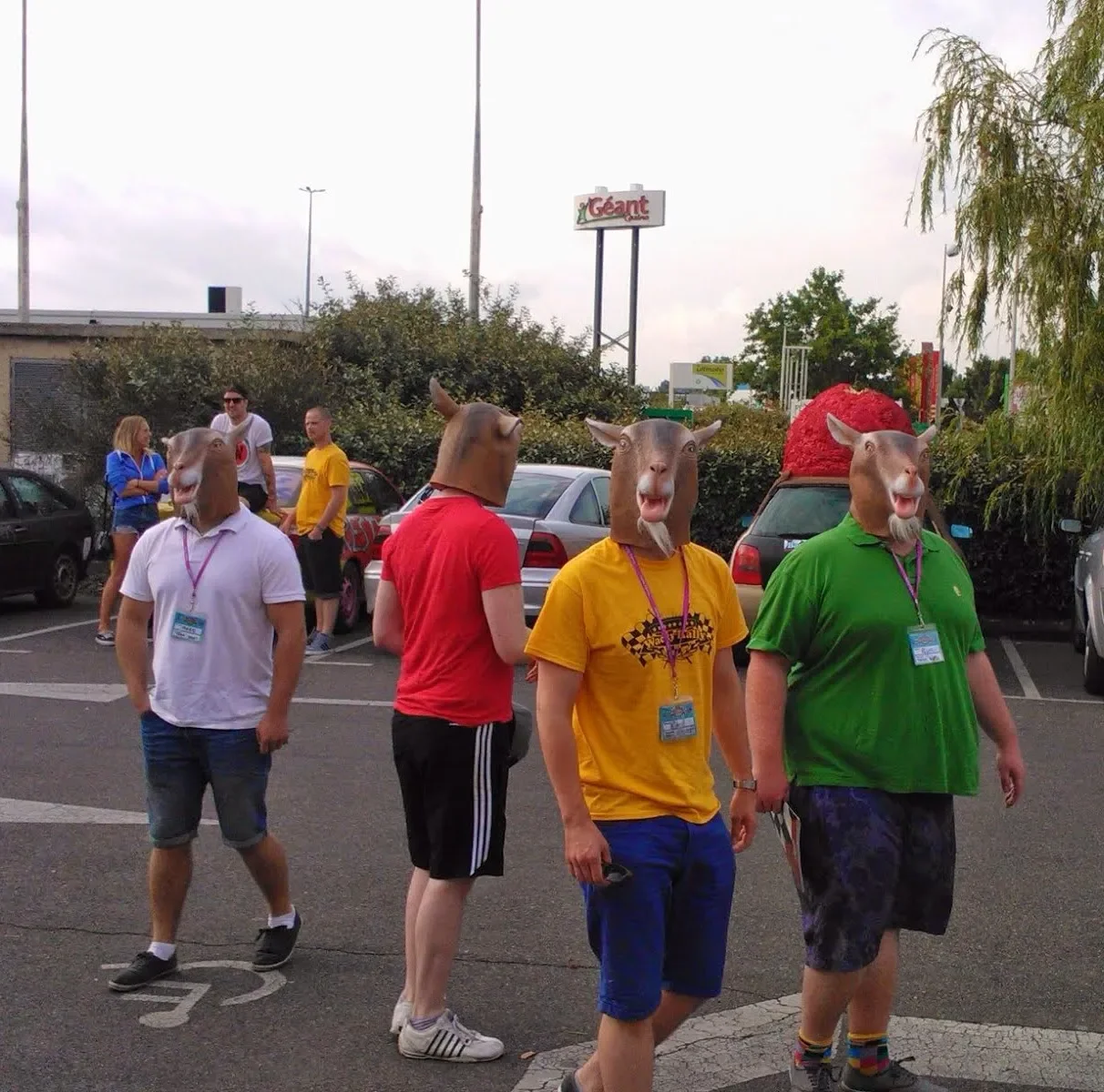 Group of people wearing animal masks, including horse, cow, and pig, walking in a parking lot during daytime.