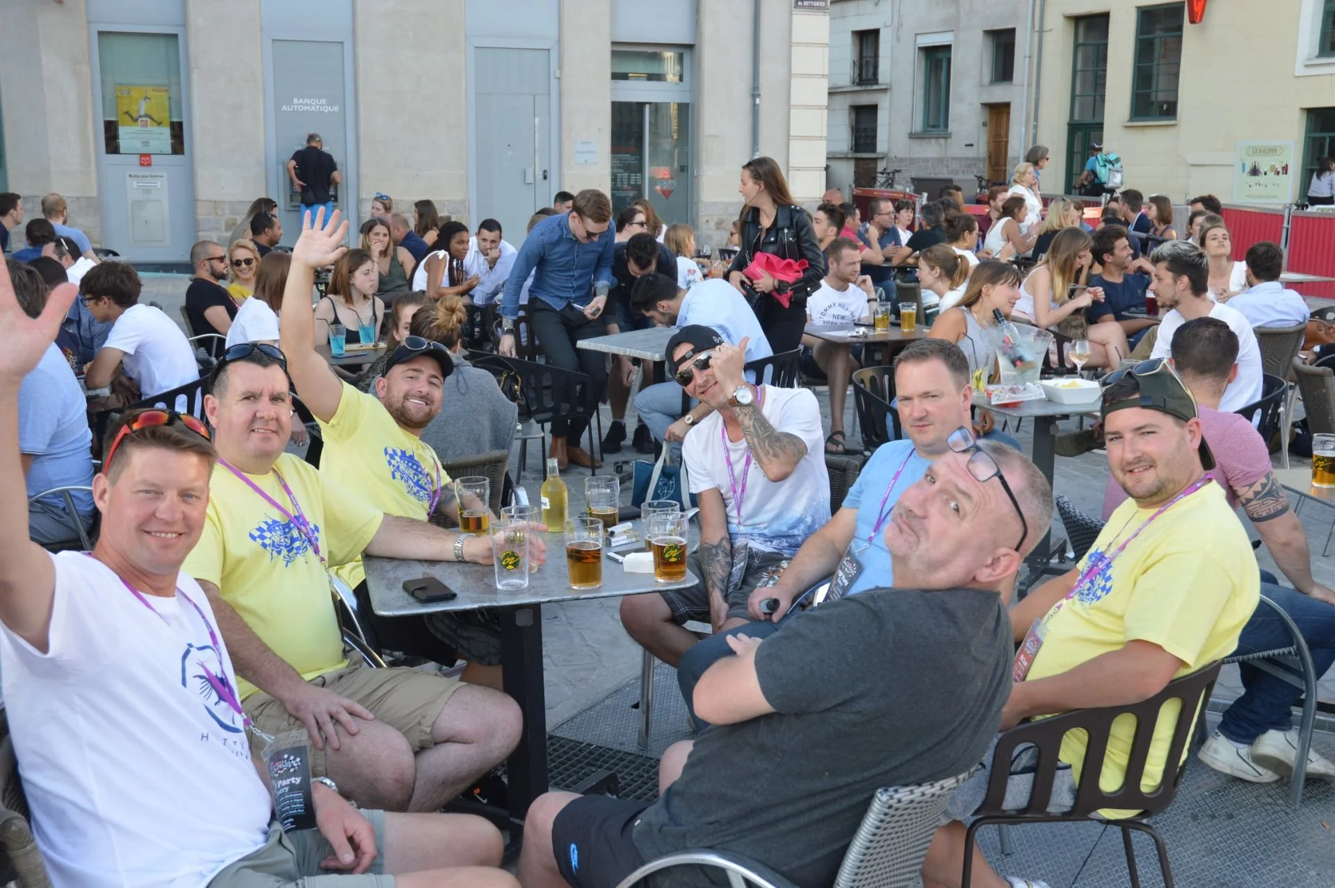 People enjoying outdoor gathering with drinks at a city sidewalk café.