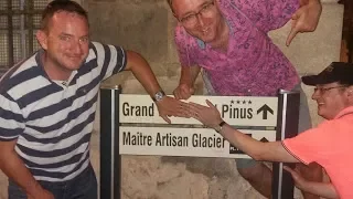 Three men near a signboard pointing at directions to the Grand Piness and Maître Artisan Glacier