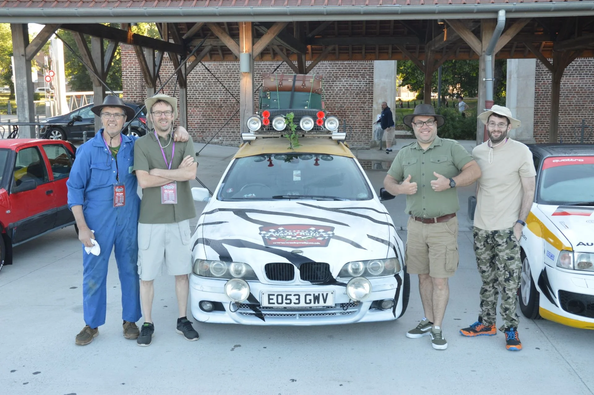 Group of five men standing in front of decorated car during a car event.