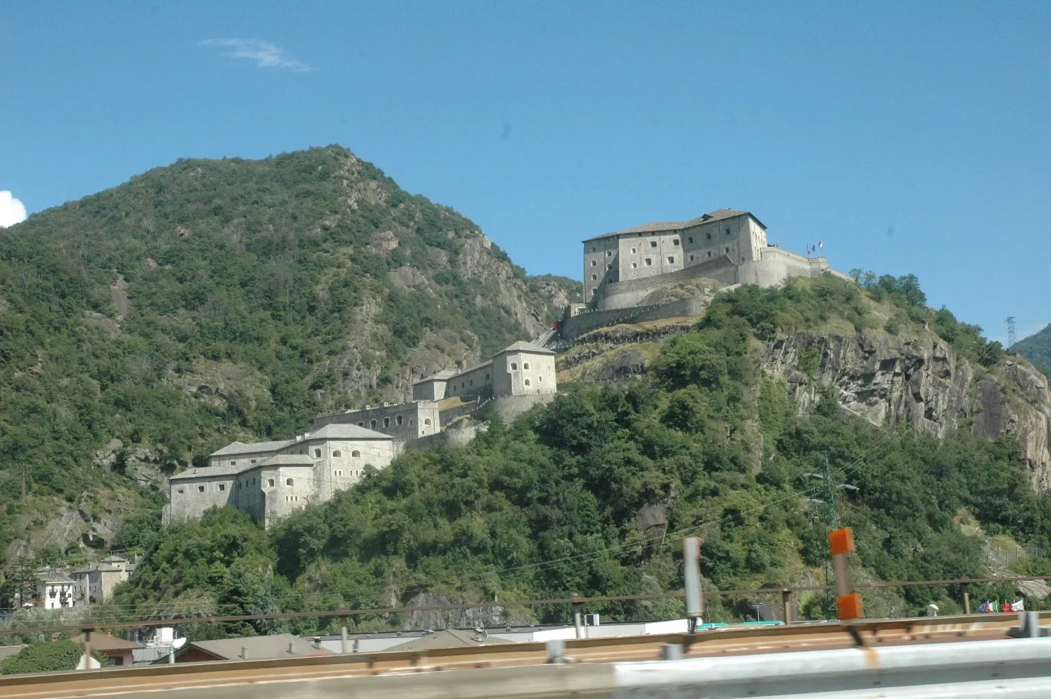 A castle on a hilltop overlooking a town with a mountain in the background.