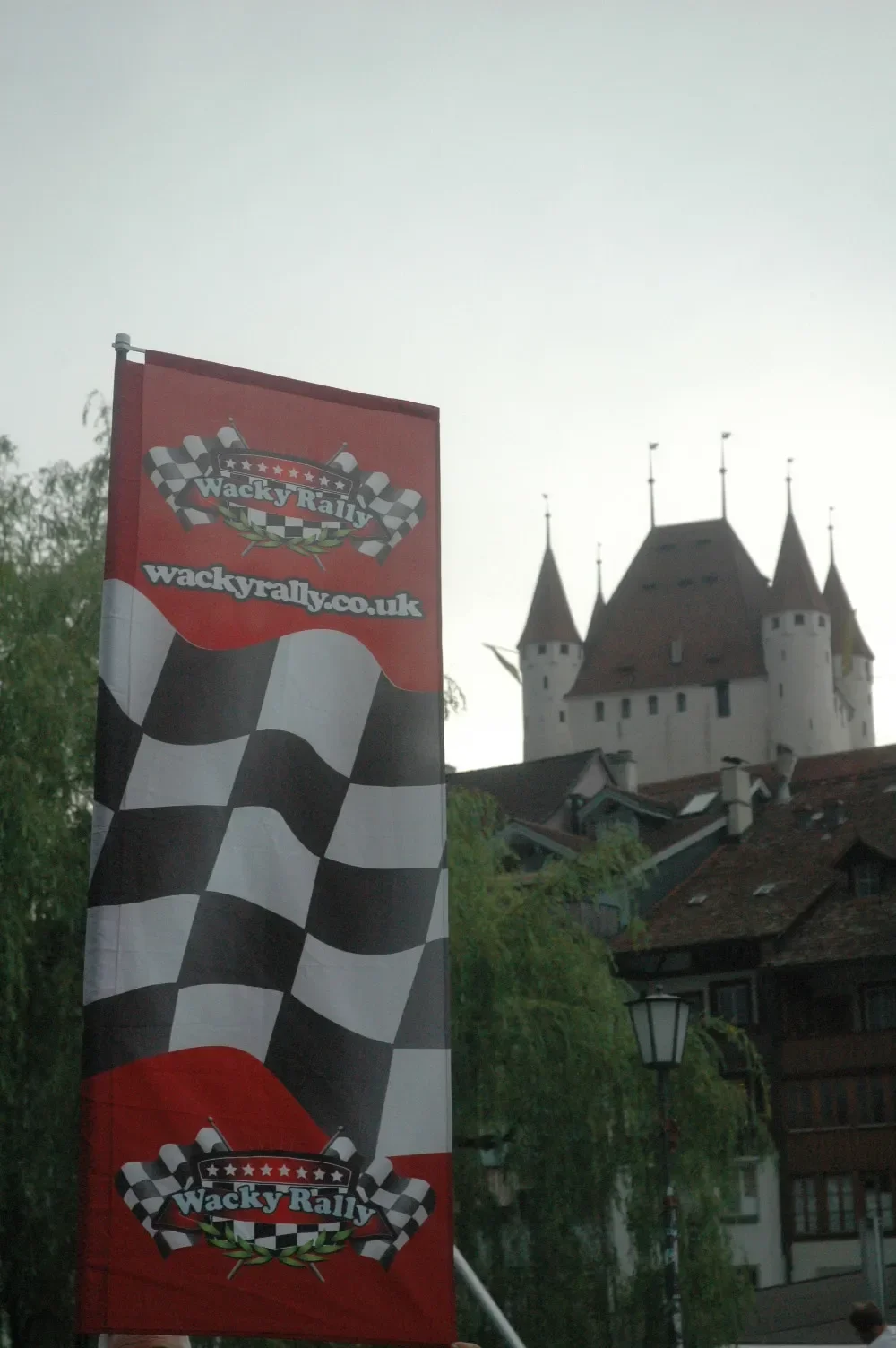 Flag with checkered pattern and Wacky Rally logo in front of a castle with pointed towers.