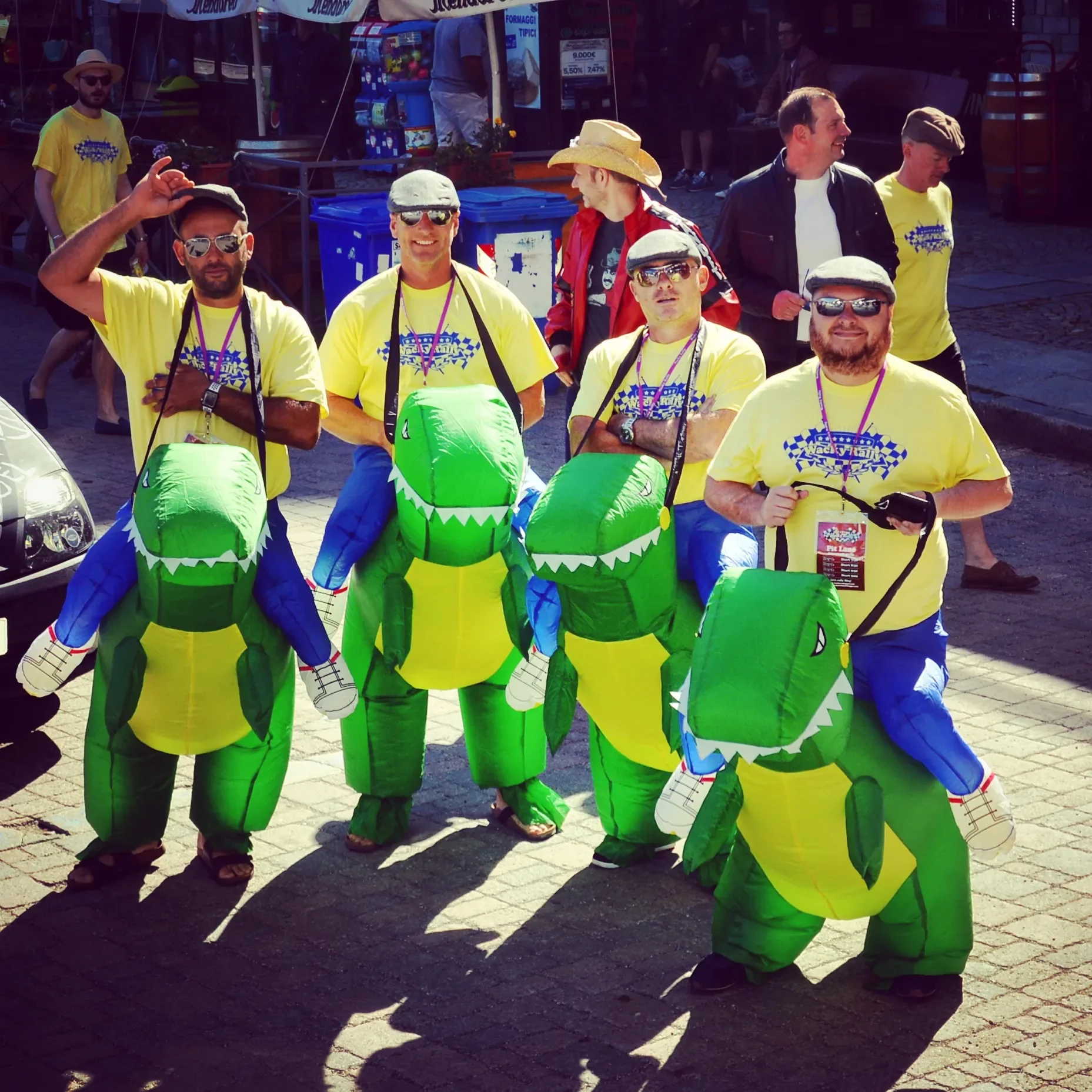 Group of people dressed in yellow T-shirts and inflatable dragon costumes at an outdoor event.