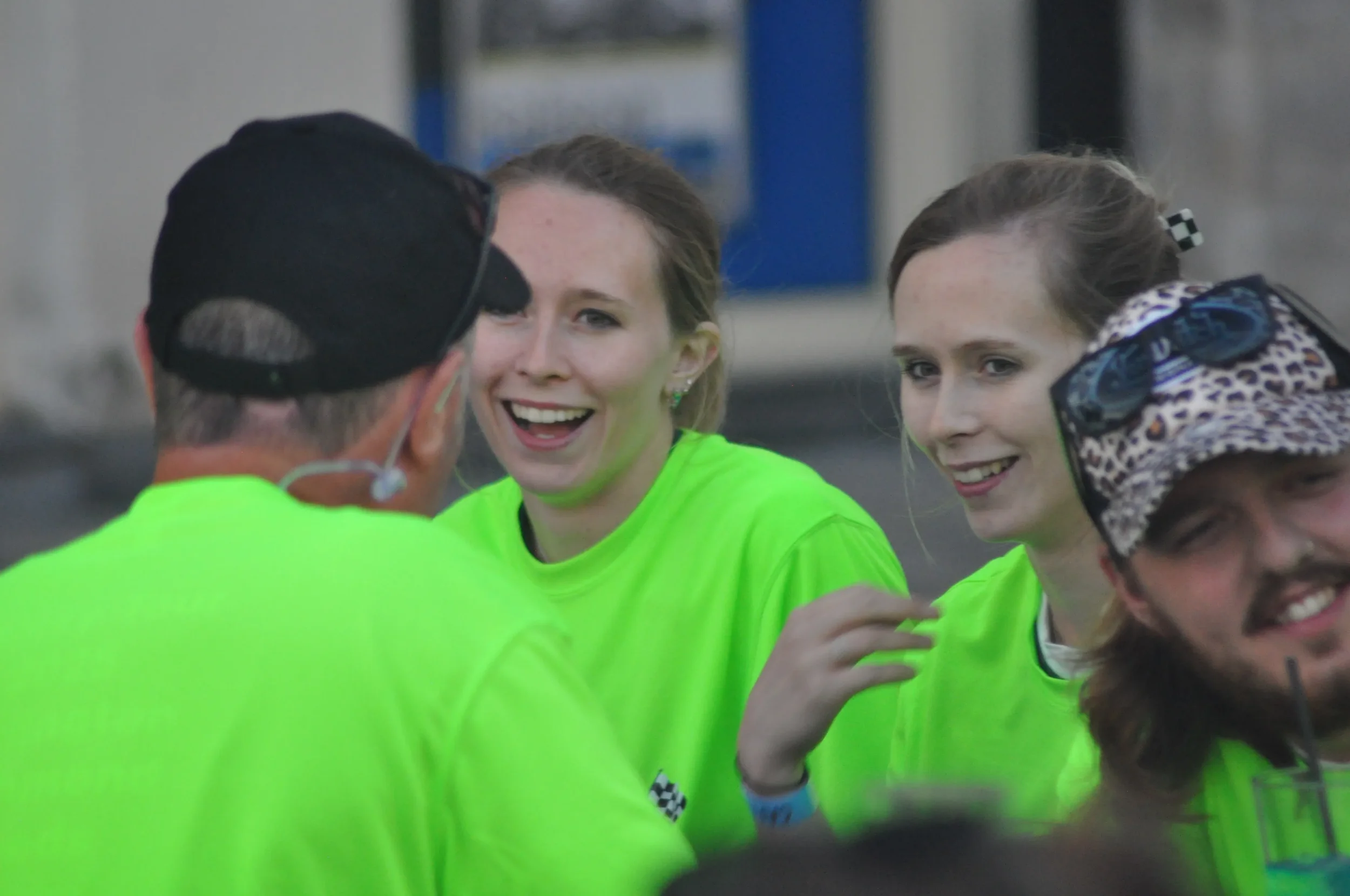 Group of people with bright yellow shirts, smiling and chatting outdoors.