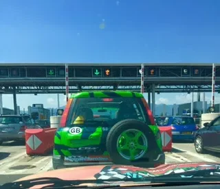 A green and black car with green wheels at a toll booth.