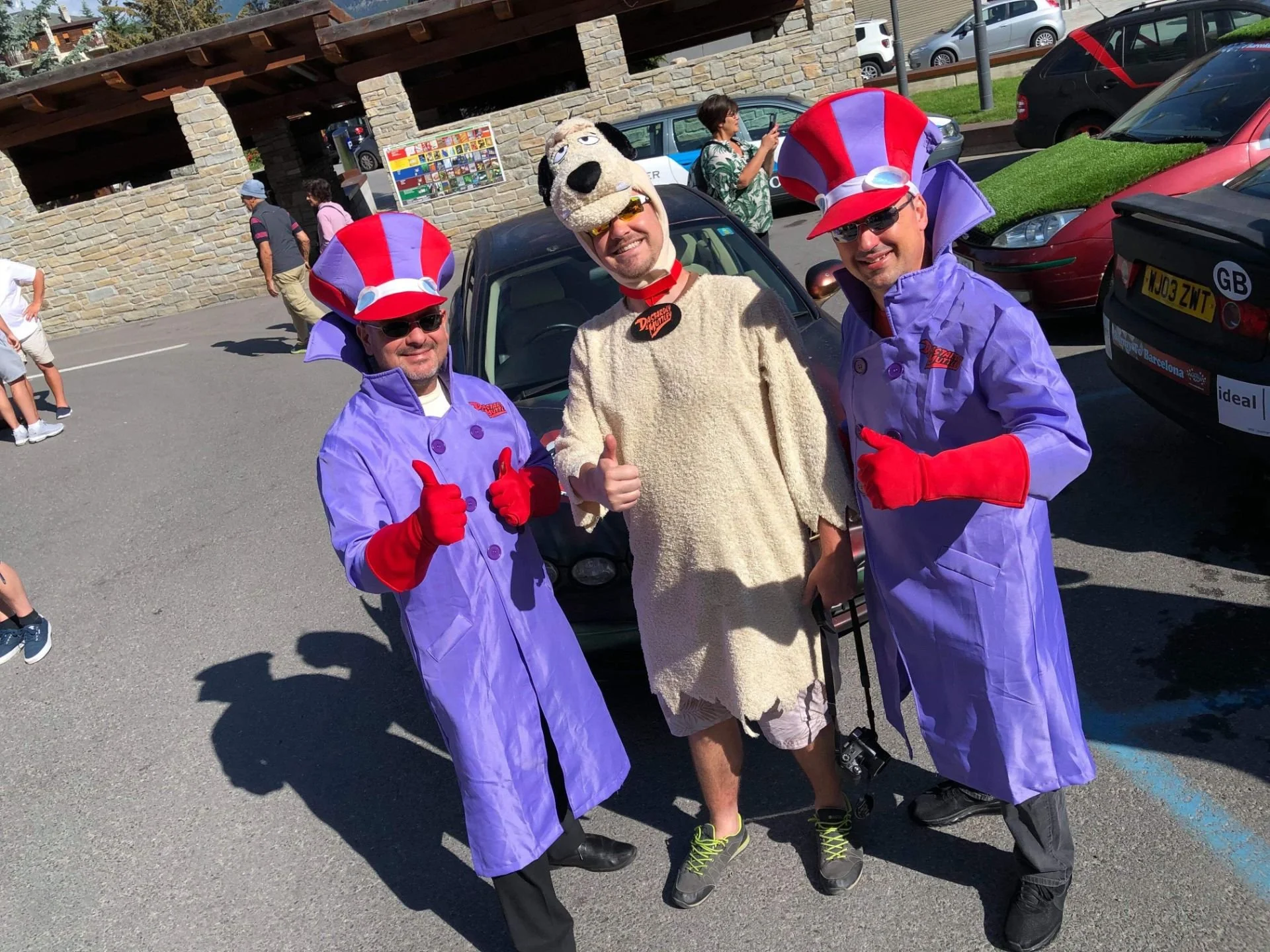 Three men in colorful costumes celebrate outdoors on a sunny day, with two dressed as characters from the movie 'The Cat in the Hat' and one in a dog costume.