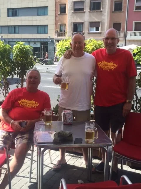 Three men enjoying drinks at an outdoor cafe.