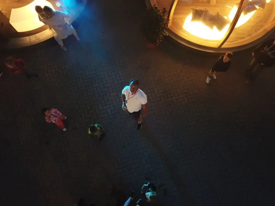 People looking up at a camera from a high angle outside a building at night.