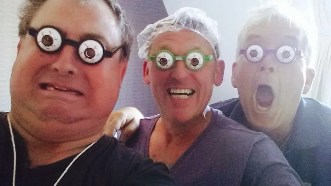 Three people smiling and wearing novelty glasses with large, cartoonish eyes, in a fun, playful setting.