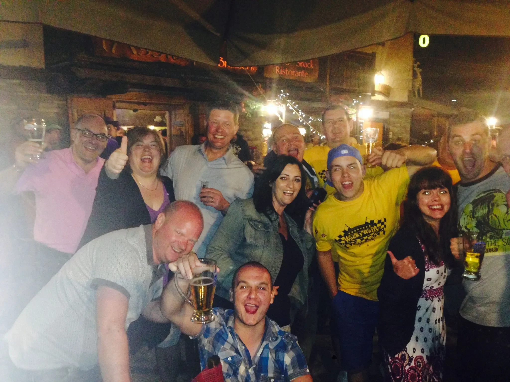 A group of people celebrating at a party or social gathering, holding drinks and smiling.