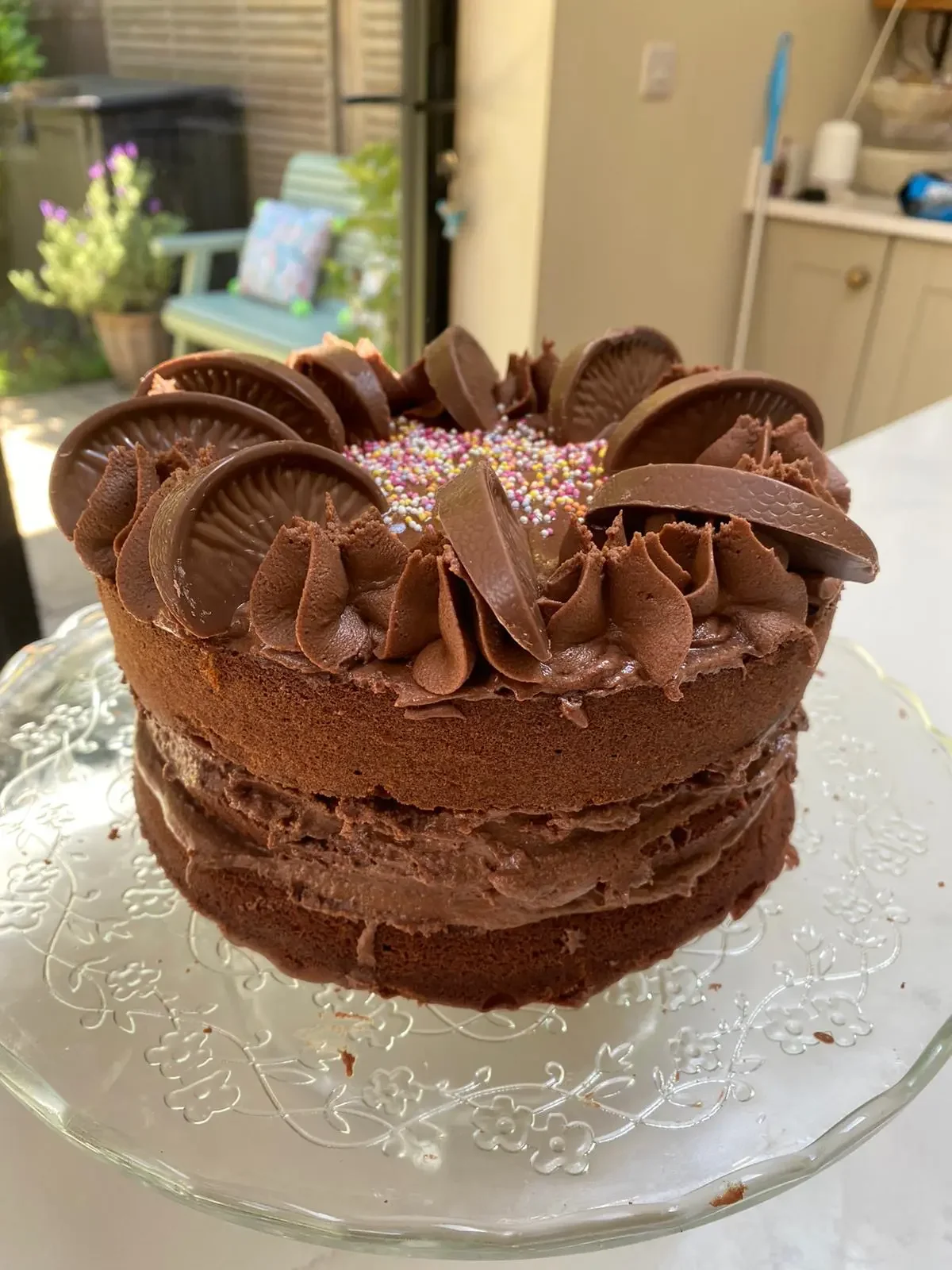 Chocolate cake with chocolate frosting and Oreos on top, decorated with colorful sprinkles.
