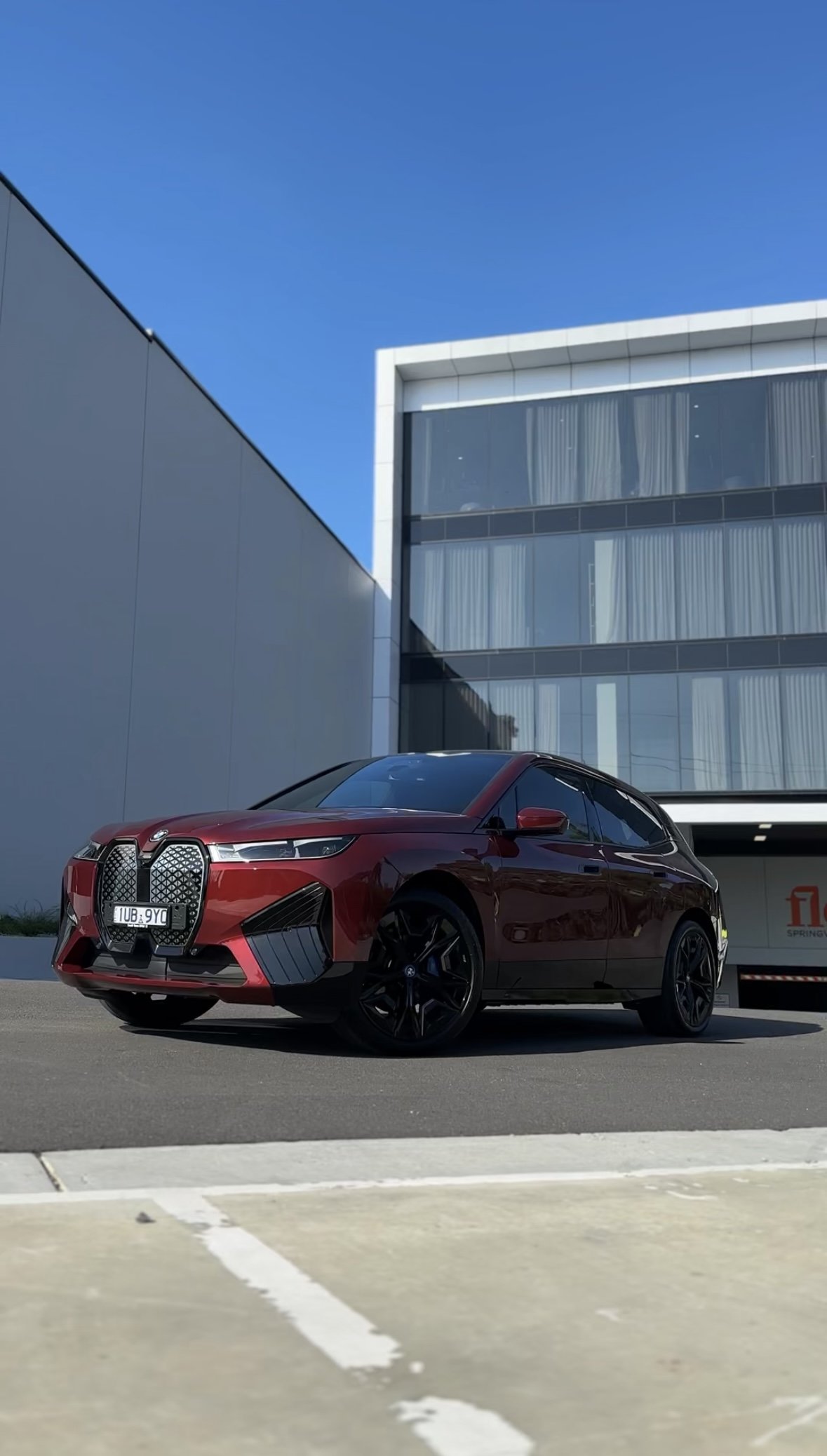 A red BMW vehicle parked outside a modern glass building