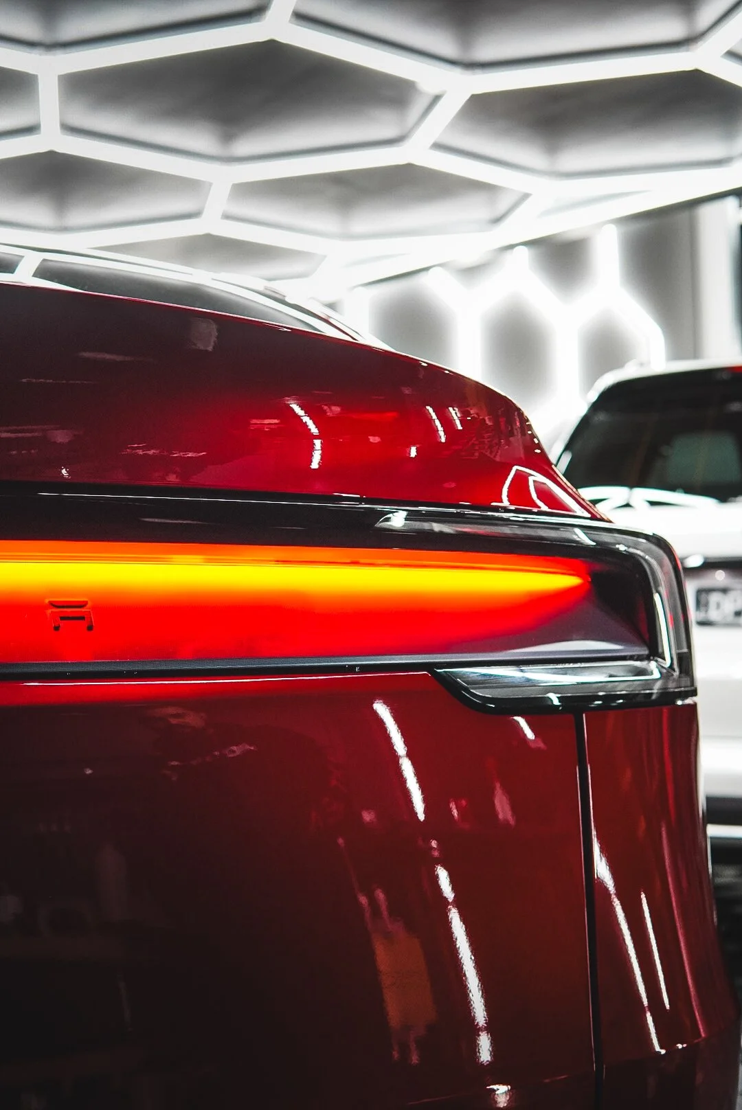Close-up of the rear end of a red car with illuminated taillight in an indoor parking garage.