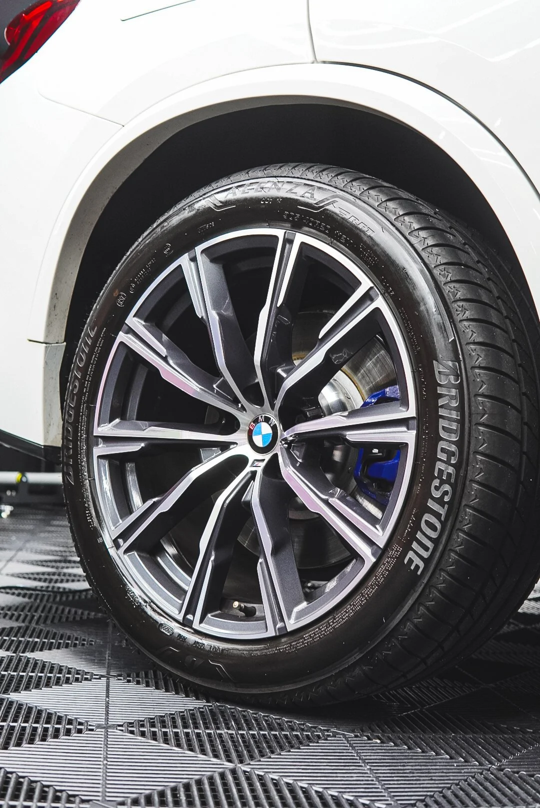 Close-up of a BMW car wheel with a Bridgestone tire, featuring a silver and black alloy rim with the BMW logo at the center,