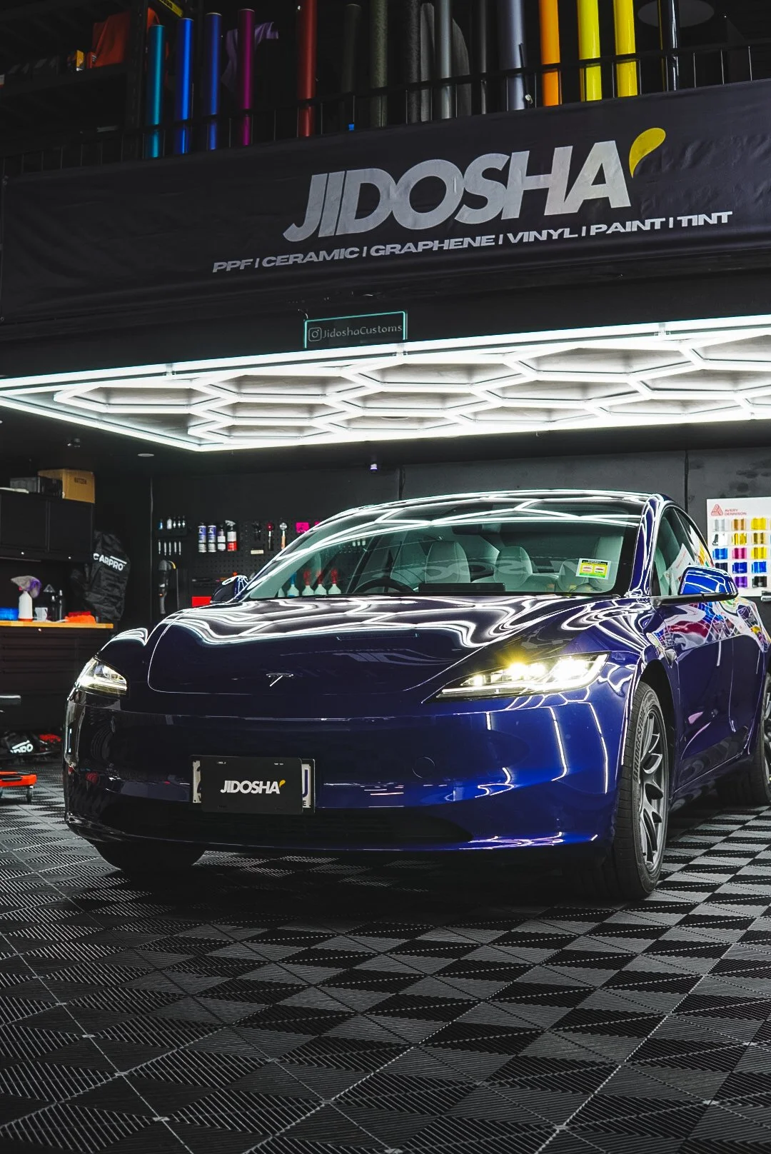 A blue Tesla car parked inside our well-lit auto detailing shop