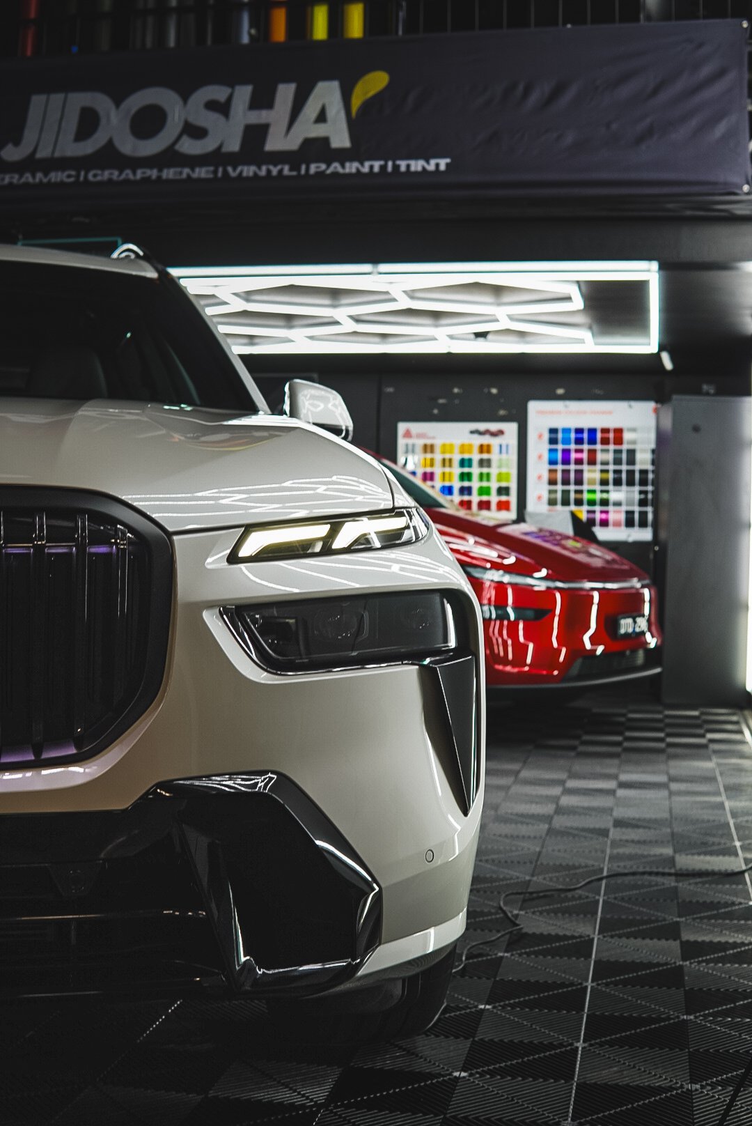 Close-up of two luxury cars, a beige SUV in the foreground and a red sports car in the backgroun