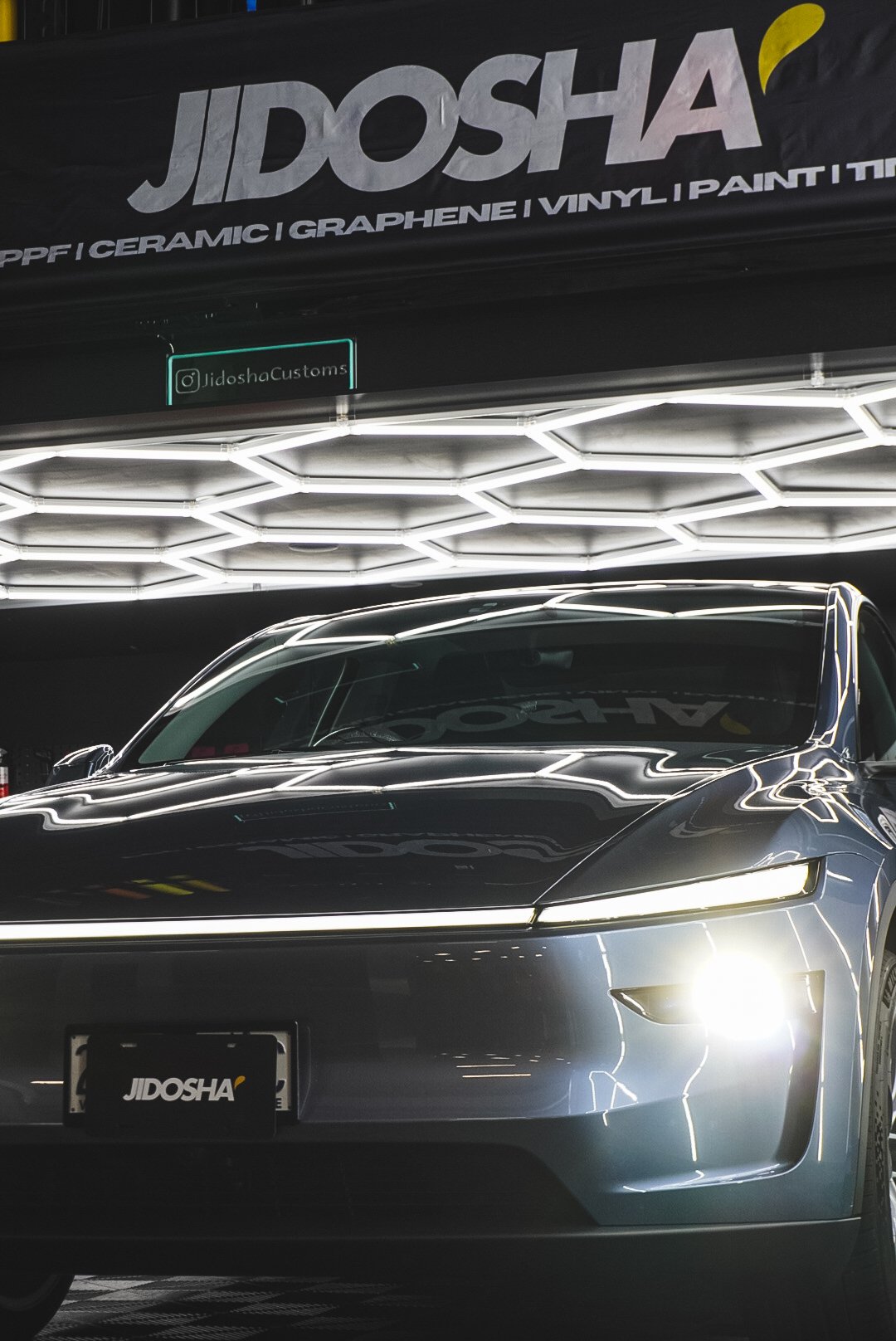 A sleek dark gray car with bright headlights