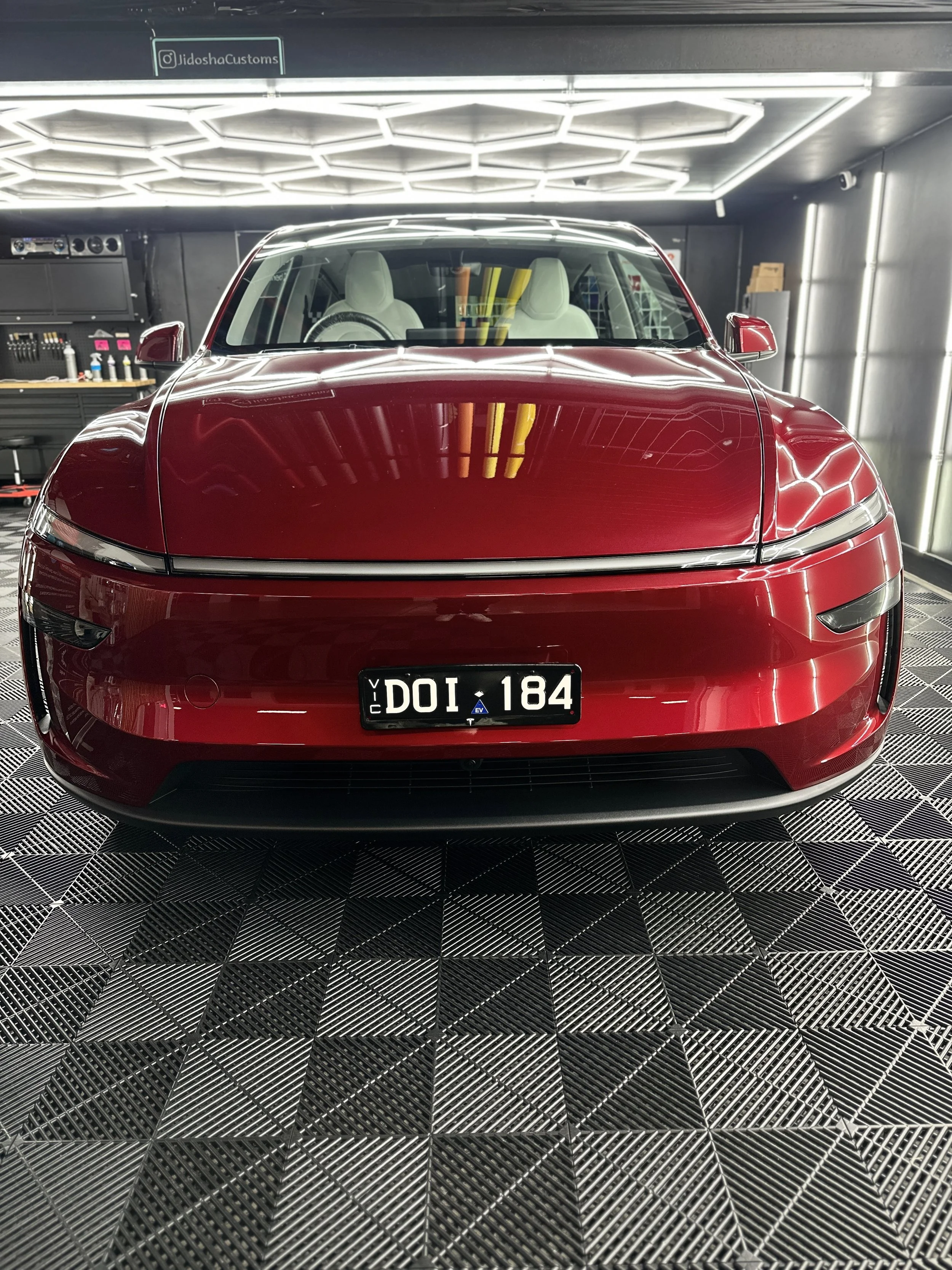 Front view of a red Tesla electric car parked in a garage