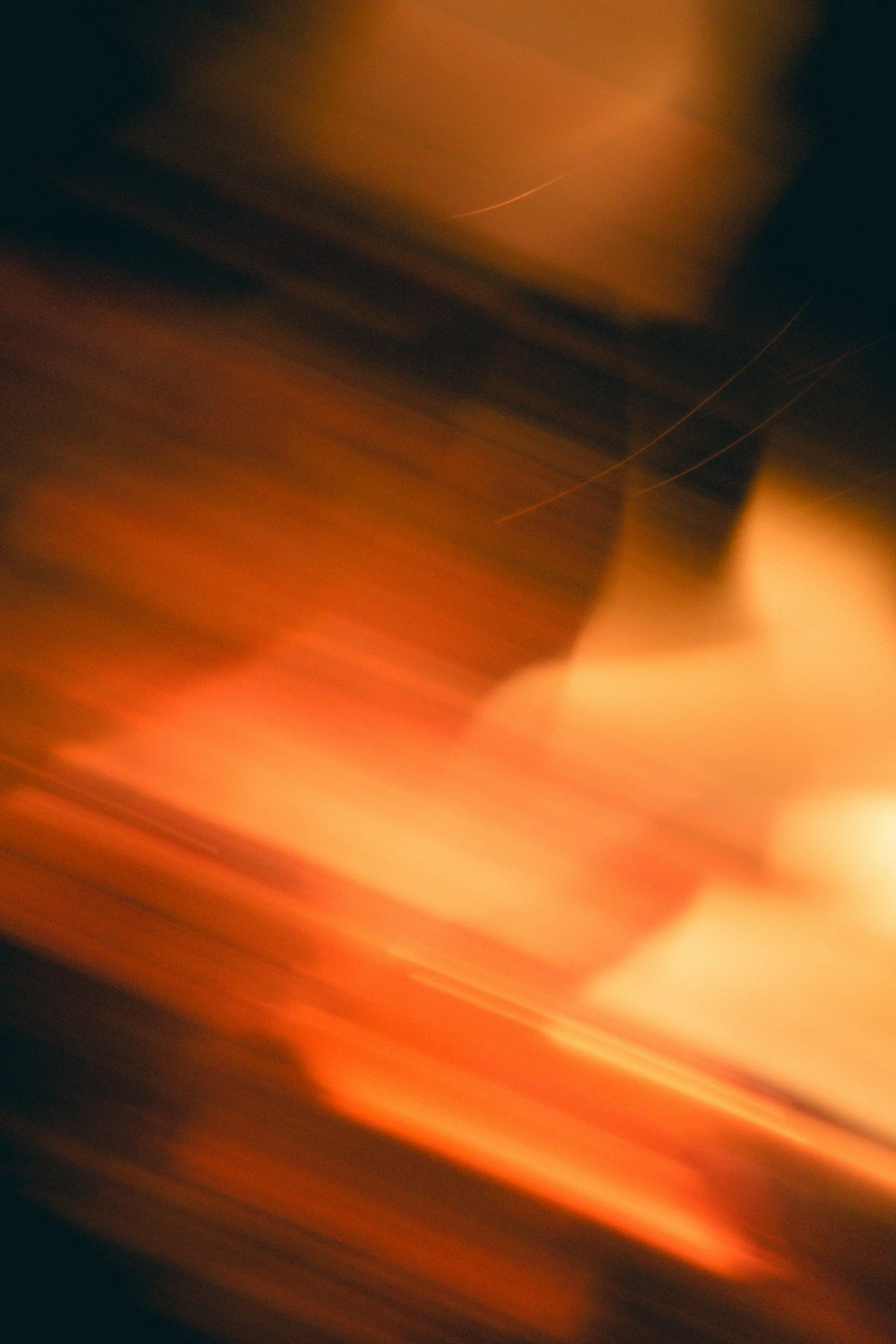 An abstract photo with blurred motion effects, displaying orange, red, and dark tones.