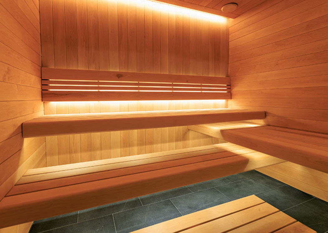 Wooden sauna interior with benches and warm lighting.