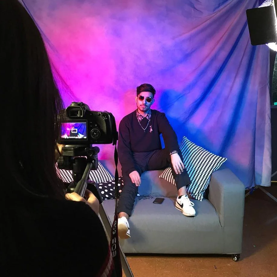 A young person poses for a portait in front of a colorful background, with dramatic lighting.