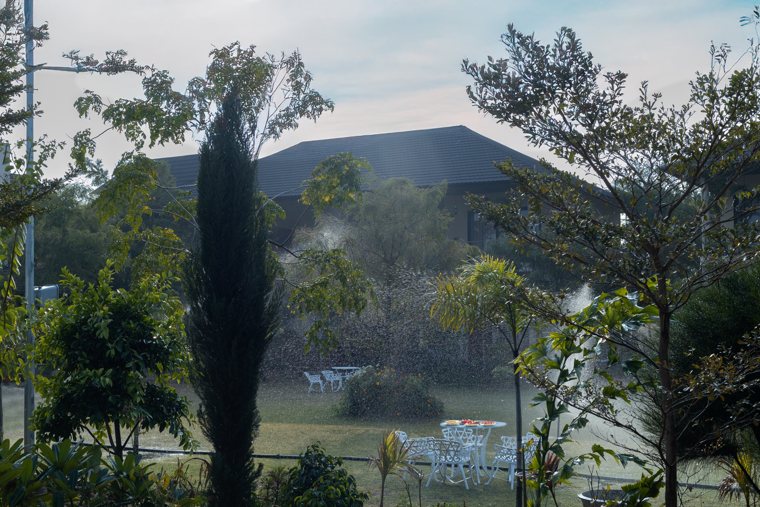 A hotel room with a four-poster bed, decorative lighting, and a central table.