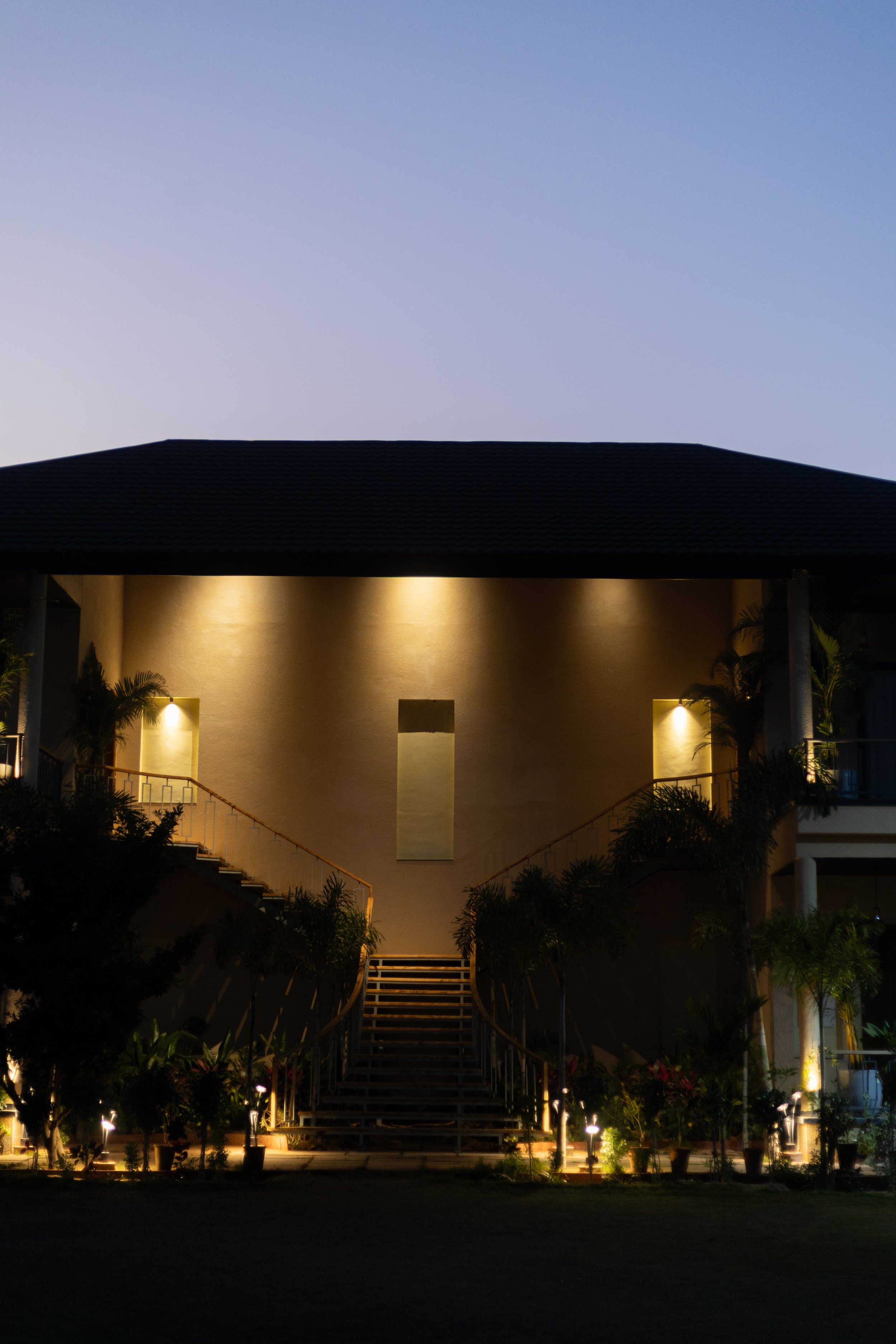 A modern building at night with exterior lights illuminating the staircase and plants.