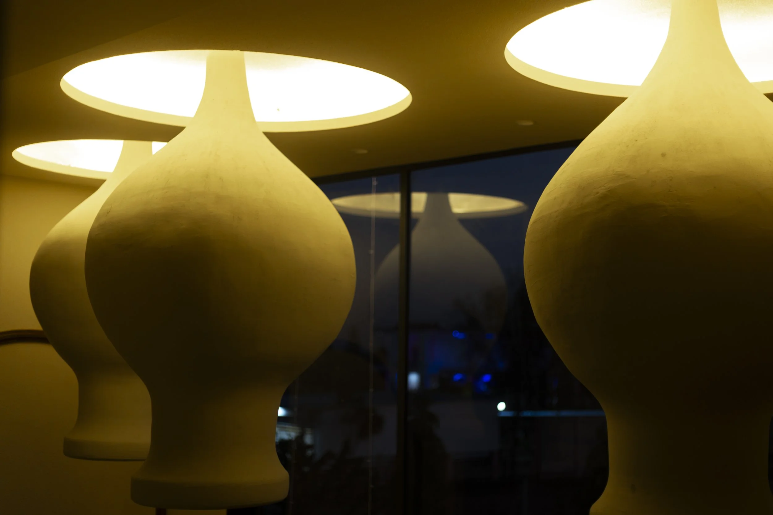 A modern house at night with exterior lighting, staircase, and tropical plants in the garden.