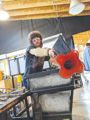 Glass artist Spencer Silva welding colorful glass into a flower shape.
