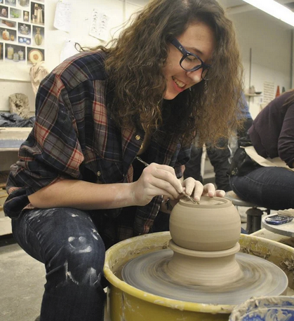 Faith Connor Byrd working on a pottery wheel in a ceramics studio.