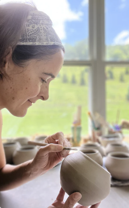 Potter Joy Tanner shaping a ceramic bowl in a pottery studio.