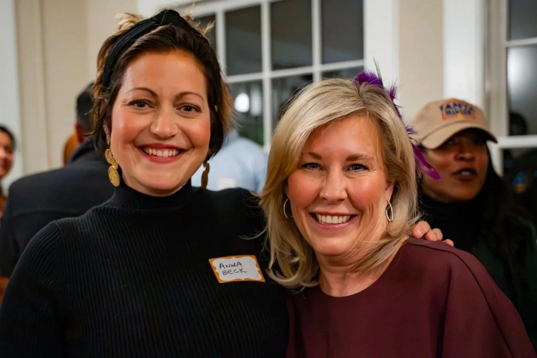 Two smiling women standing close together at an indoor gathering to promote Public Service to Public Power.