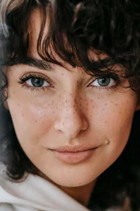 Close-up portrait of a woman with curly dark hair and blue eyes.