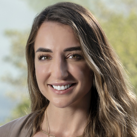 Young woman with long brown hair smiling outdoors