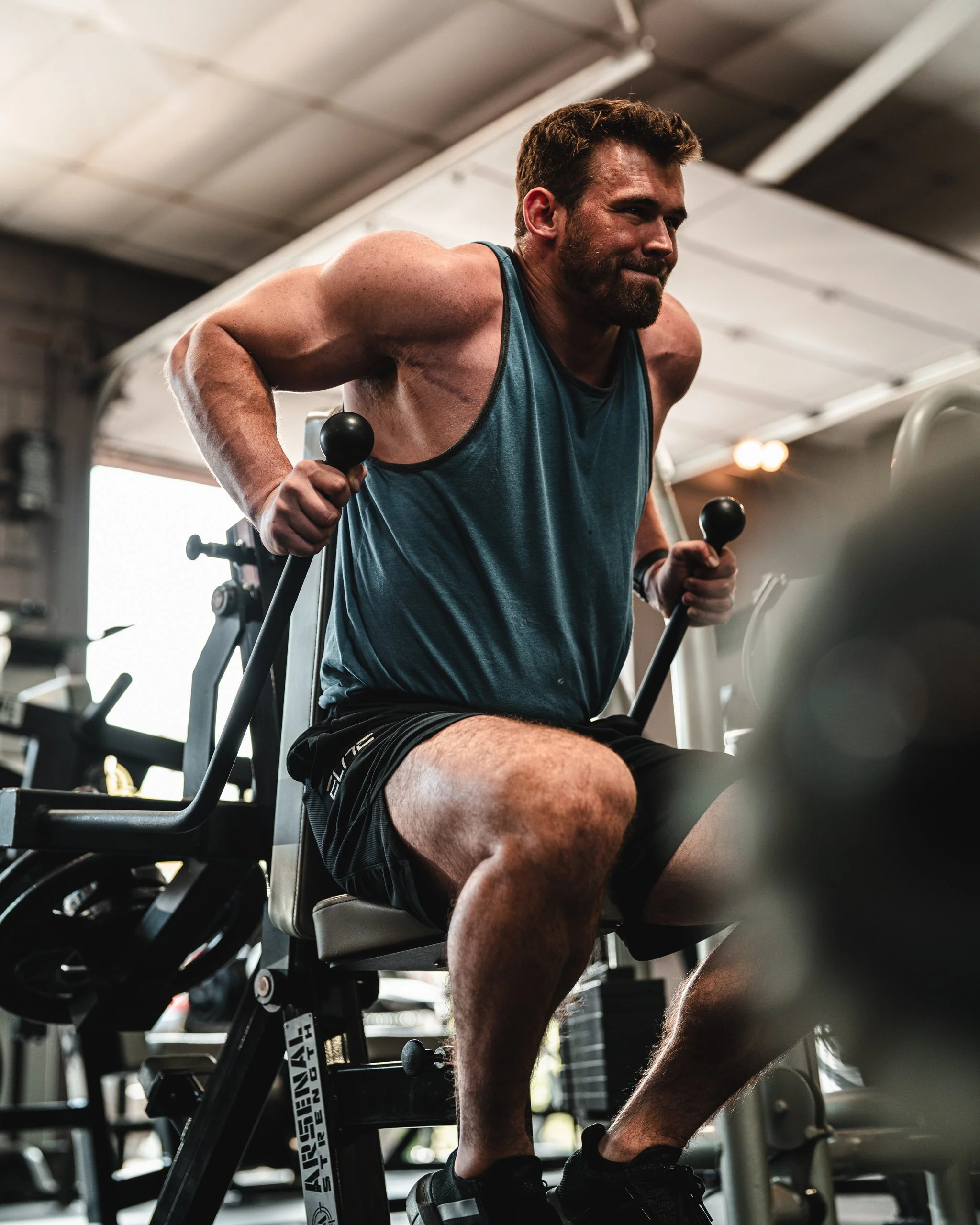 Man working out on a seated exercise machine at a gym.